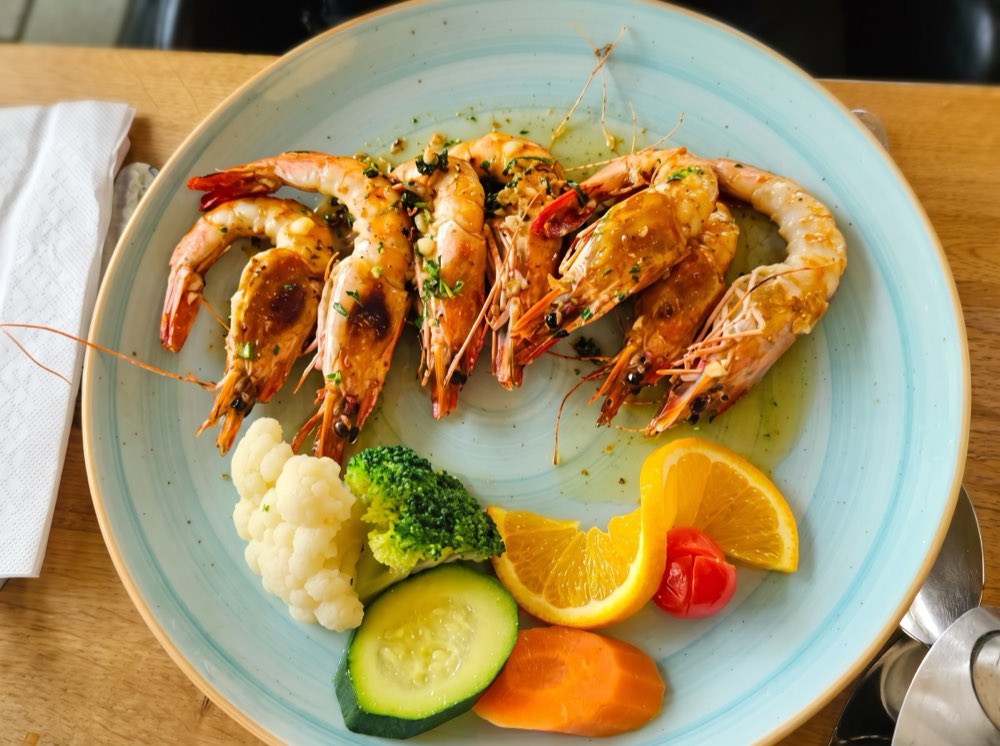 Gebratenes Fischfilet mit Kräutern und Zitrone auf einem hellen Teller.