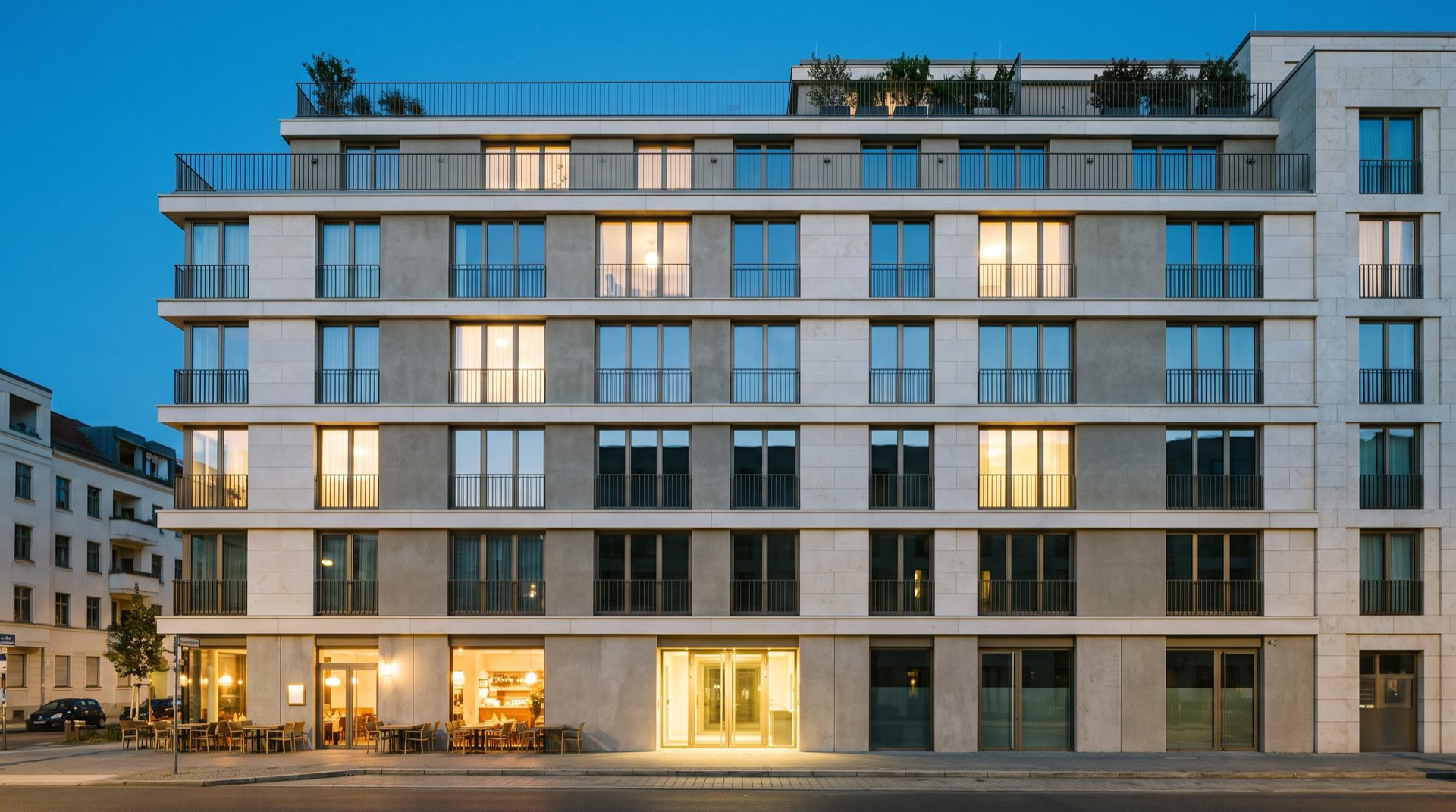 Die Fassade des Quartiers Q5 in der Abenddämmerung, warm erleuchtete Fenster über einer ruhigen Wohnstraße.