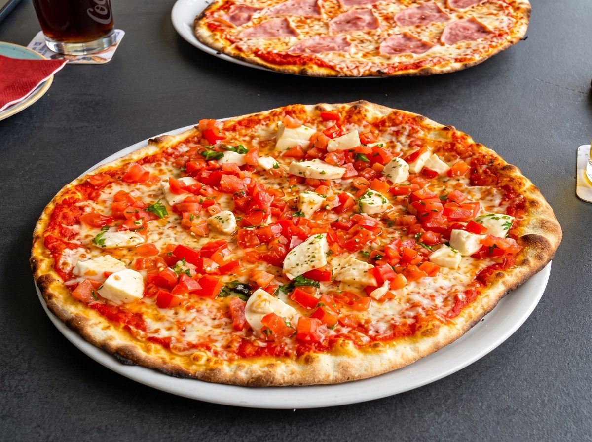Pizza aus dem Ofen, luftiger Rand mit dunklen Blasen, in der Mitte Basilikum.